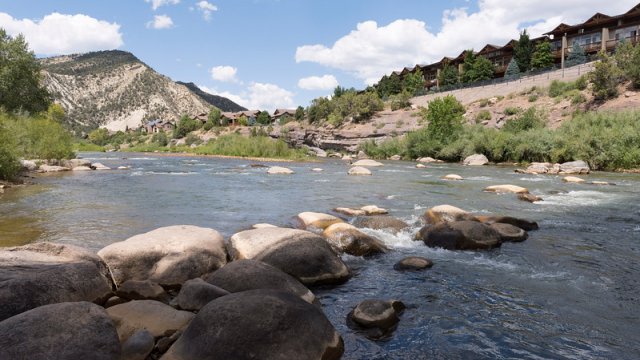 scenic photo of mountain stream with many boulders in the foreground