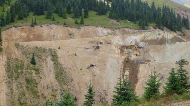 Looking across a vally, the opposite slope is a mostly dirt face with roads cut diagonally.