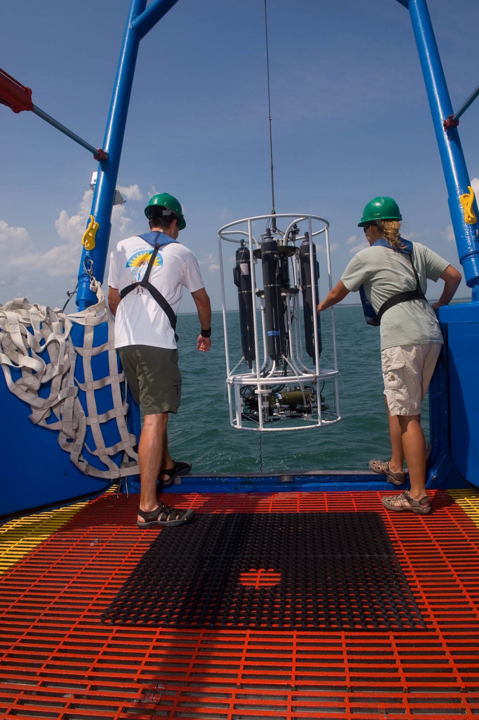 Field crew members carefully lower a multi-probe instrument to take measurements of coastal water quality.