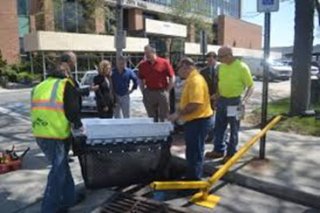 Catch basin fabric insert being installed in a street-entry storm drain.