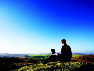 Person with laptop looking down from hill