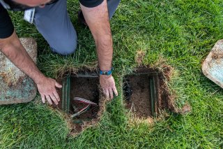 Man inspecting outdoor irrigation valve box.