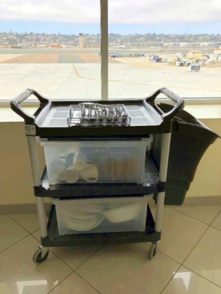 Rolling cart with plastic tubs filled with reusable dishes and silverware