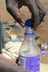 Mercury poured from cap into soda bottle.