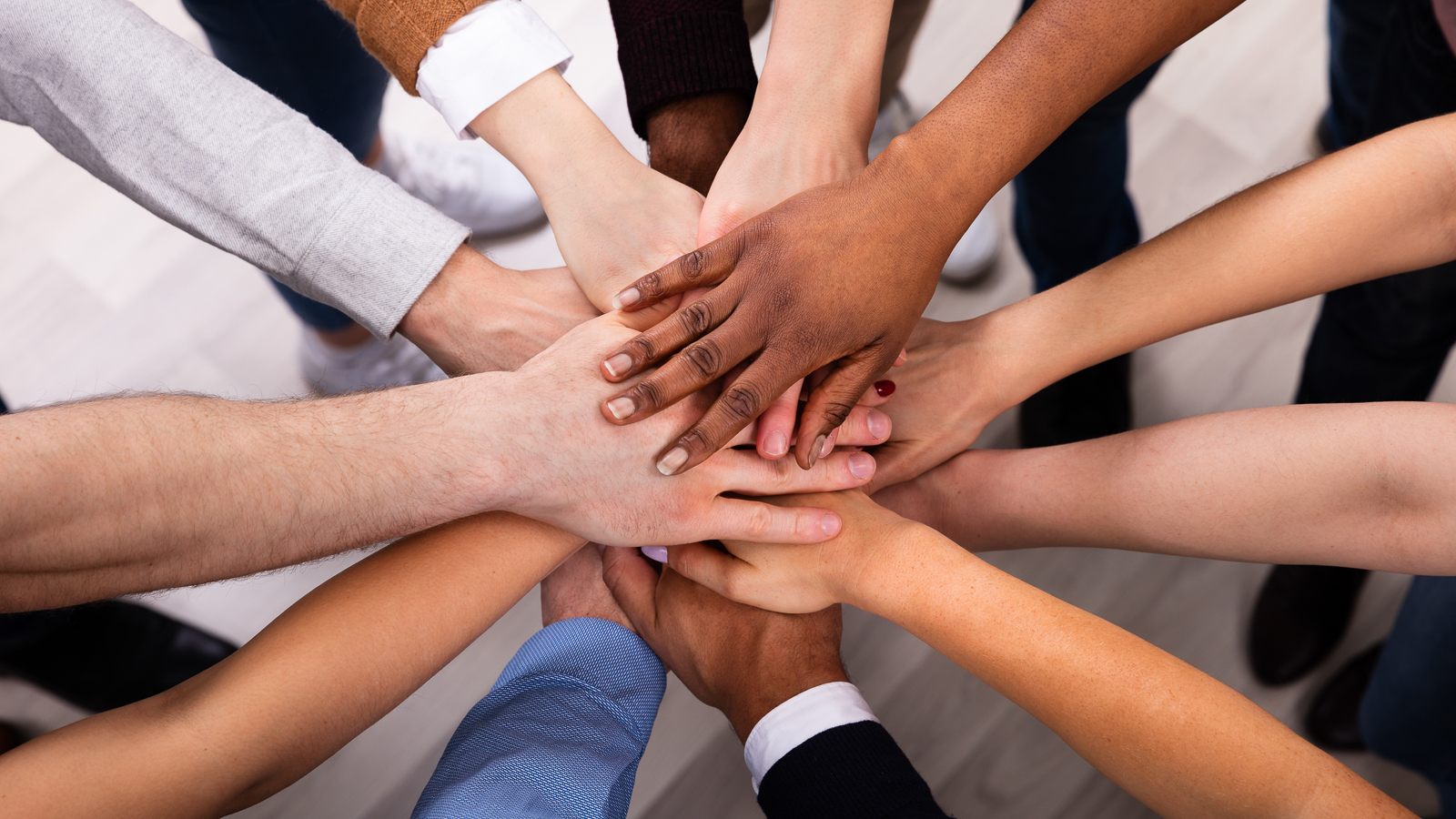 Image of everyone working together putting their hands a top of one another. 