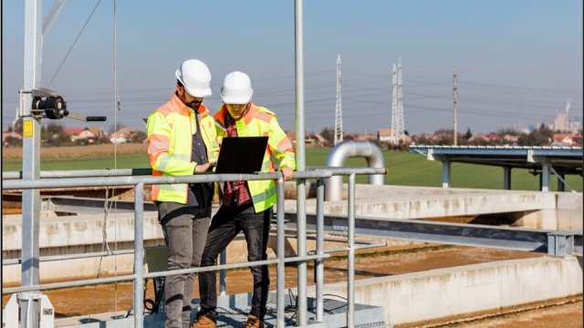 Workers reviewing plans standing next to a wastewater treatment plant