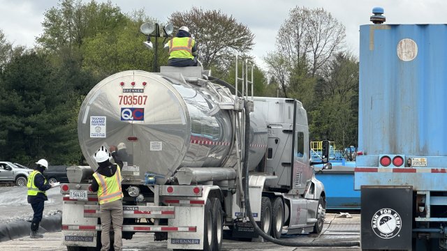 Liquid waste is loaded, labeled, and logged within a secondary containment area.