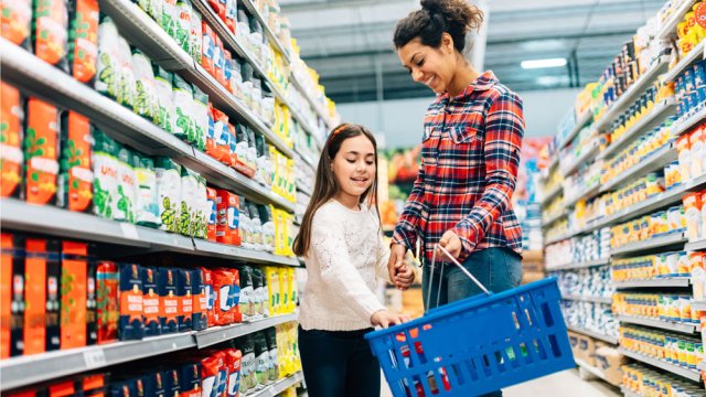 Child and adult in grocery store aisle with shopping basket