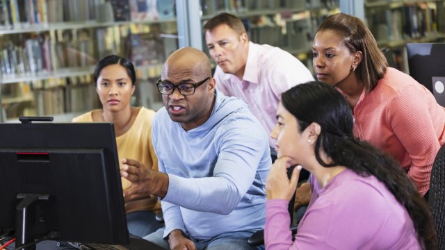 Group of adults look at a computer together