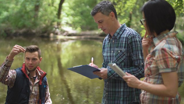 Researchers in pond collecting water samples