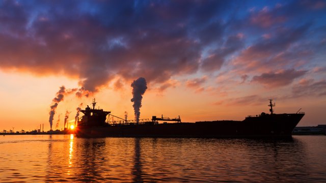 Silhouette of a cargo ship in front of a sunset