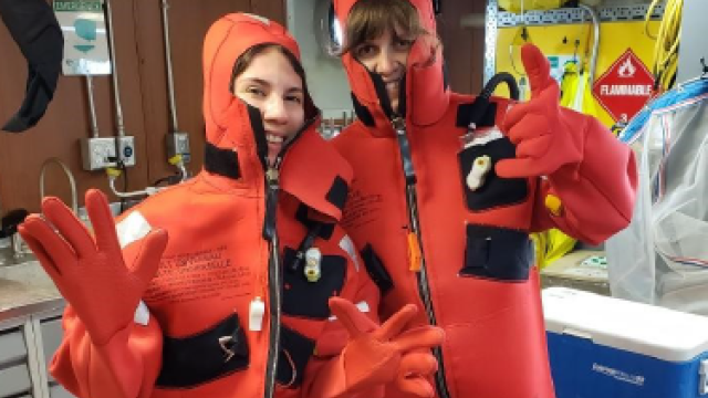 A couple of student interns in orange jumpsuits in a laboratory.