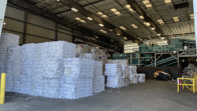 several baled stacks of paper inside a recycling facility warehouse