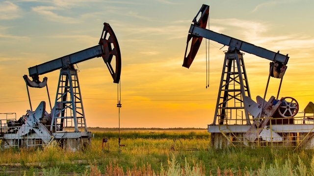 Two pumpjacks with the sun setting in the distance