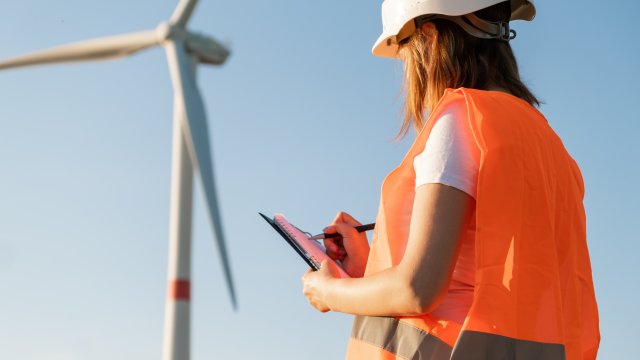 Worker taking notes in the foreground with a windmill in the backing