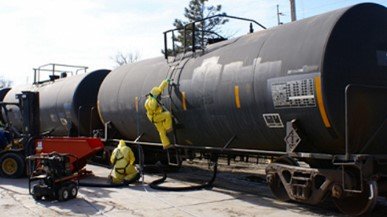 railcar tanks with workers climbing up ladder on tank 