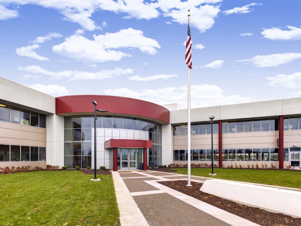 A paved walkway leading to a building and a blue cloudy sky.