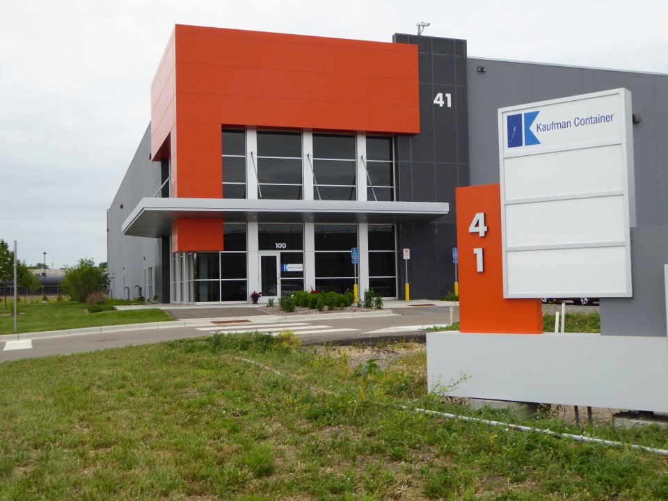 A gray and orange building and a sign saying "41, Kaufman Container"