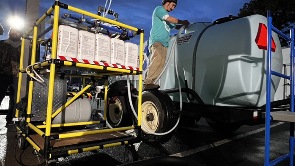 A tanker truck is hooked up to the WOWCart for treatment of the water.