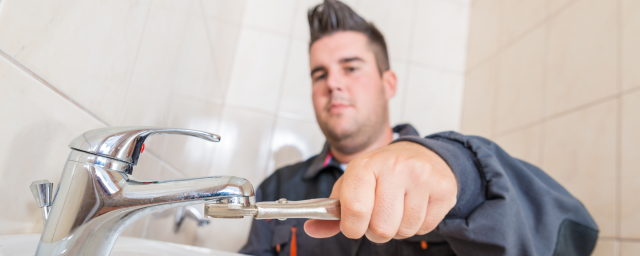 A man uses tools to fix a faucet