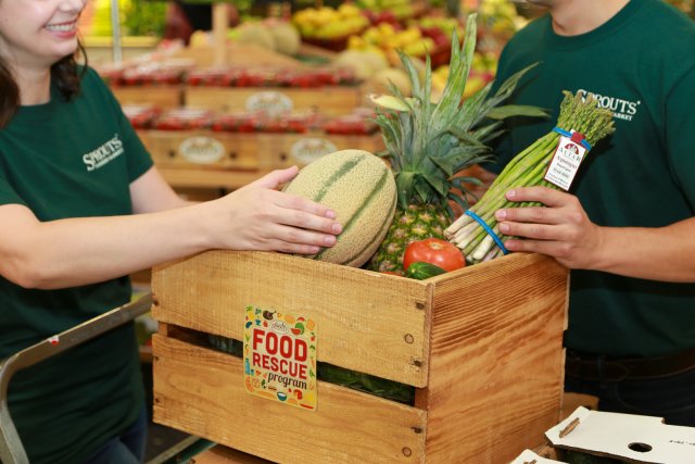 Closeup photo of a man and woman filling a box of produce. 