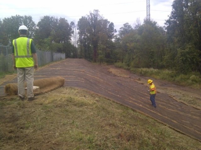 Photograph showing workers in yellow vest constructing berm reinforcement