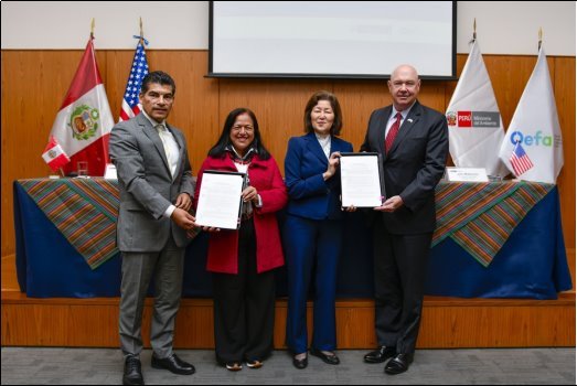 US EPA and Peru OEFA Representatives sitting at table signing the MOU with their country flags in the background.