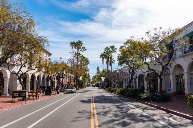 This image buildings straddled by a road with bike lane, parking lanes, sidewalks and trees