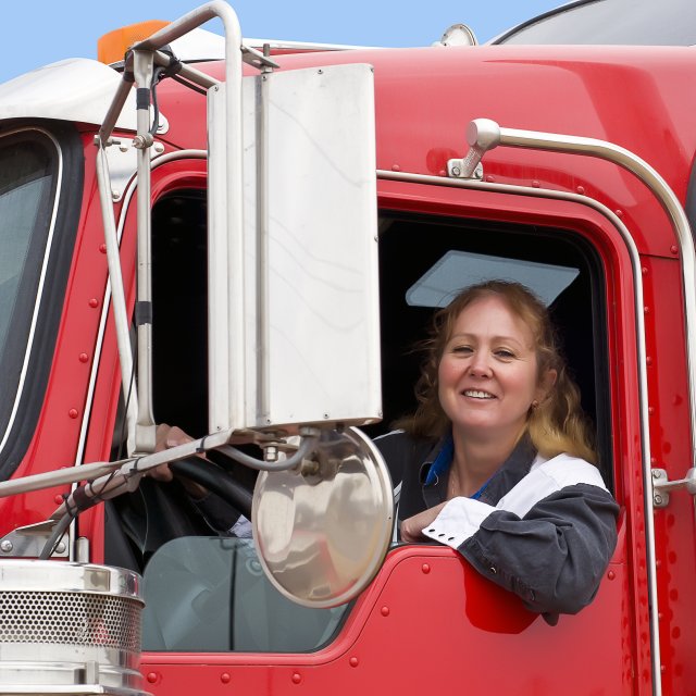 Woman truck driver in a red truck cab.