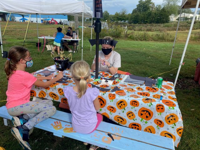 AJ sits at a picnic table with two students teaching them about bats