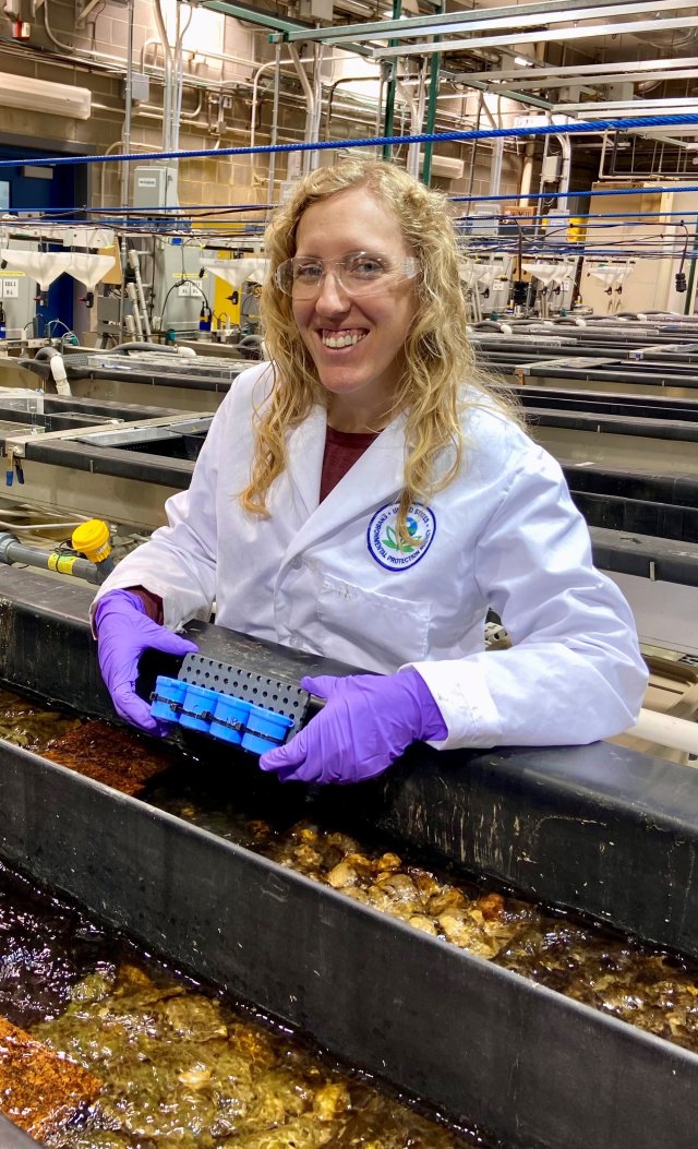 epa researcher chelsea hintz working in the lab smiling posing with a research tool