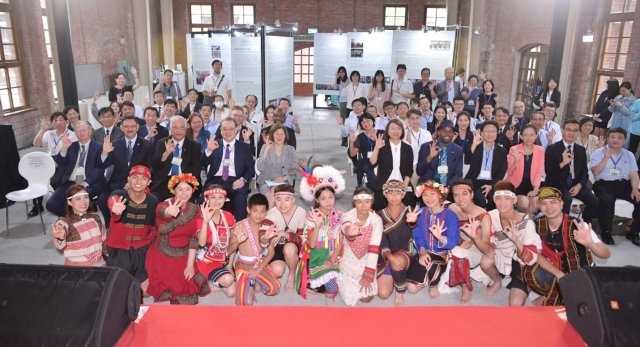 Participants of International Environmental Partnership sitting down in rows facing the camera smiling and holding up a Taiwan hand sign.