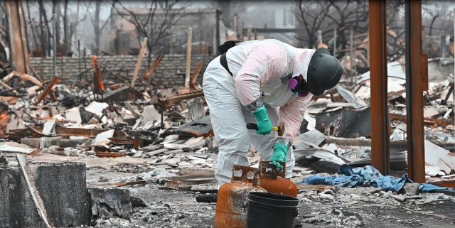 EPA Team member removing the valve from a propane tank at the burn site so that it can be processed for removal