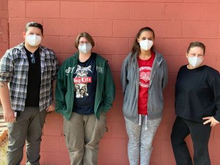 Recent job training graduates in Hayden, Arizona: Four people stand in front of a red cinderblock wall