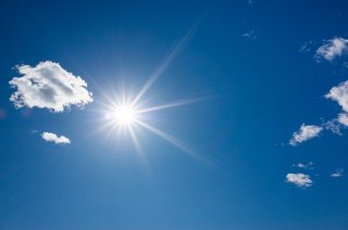 Blue sky with shining sun and a few white clouds