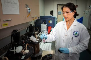 Photo of a female researcher using a microscope.