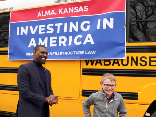 Administrator Rrgan standing in front of a bus with a child