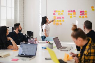 Lady stands before a white board organizing sticky notes