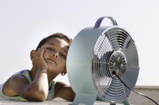 Young child sits in front of a fan