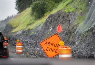 Abrupt Edge traffic sign on road with erosion from precipitation