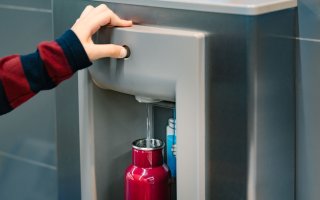 Filling up a red reusable water bottle