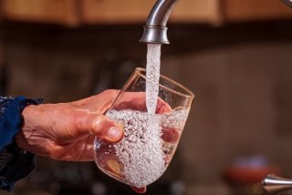 stock image of a hand holding a glass of water filling it up from a faucet