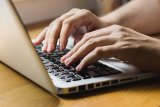 Hands typing on the keyboard of an open laptop computer